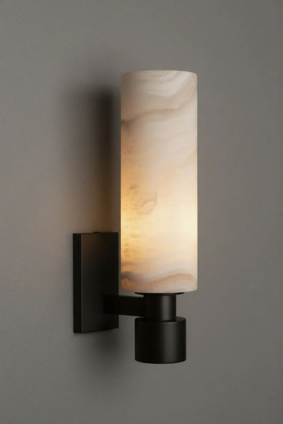 Wall-mounted light fixture with a cylindrical marble-like shade with matte black base LED on a gray wall.