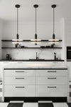 Modern kitchen with brushed dark pewter finish Alabaster LED pendant lights, white cabinets, and a checkered floor.