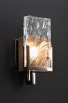 A wall sconce with a bronze finish and clear crystal glass, featuring a warm glow.