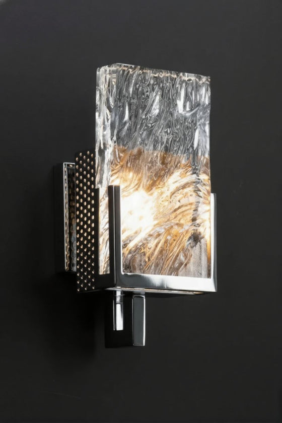 Decorative Chrome wall sconce with textured glass shade on a black background