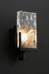 Modern matte black wall sconce with textured glass shade on a black background