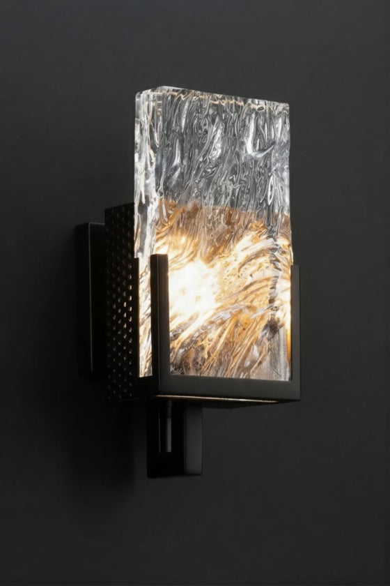 Modern matte black wall sconce with textured glass shade on a black background