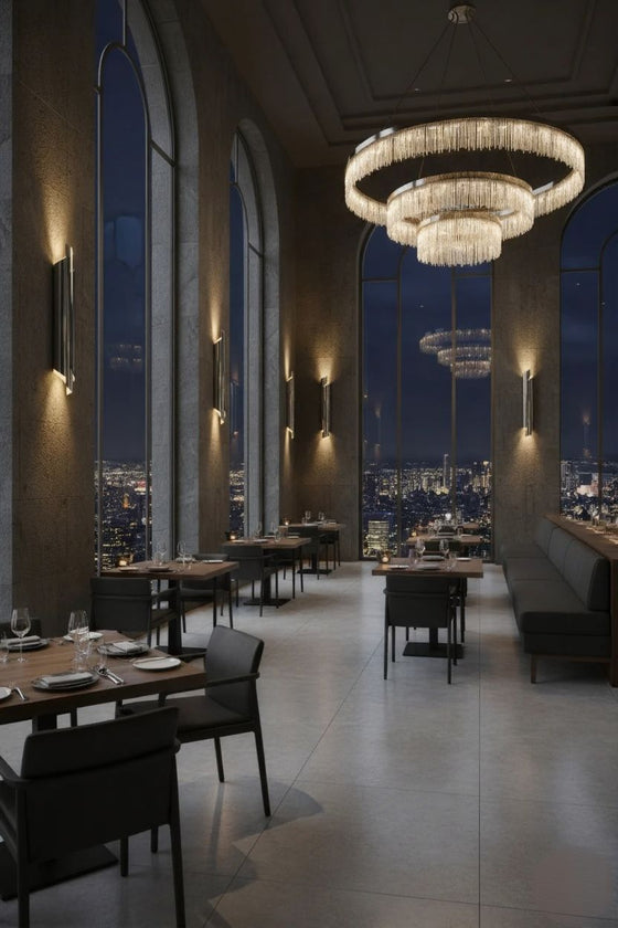 Luxurious restaurant interior with a large chandelier and cityscape view. Metal wall sconces.