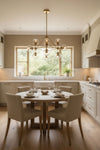 Modern kitchen with a round dining table and chairs, featuring a satin brass with glass globes chandelier and large windows.