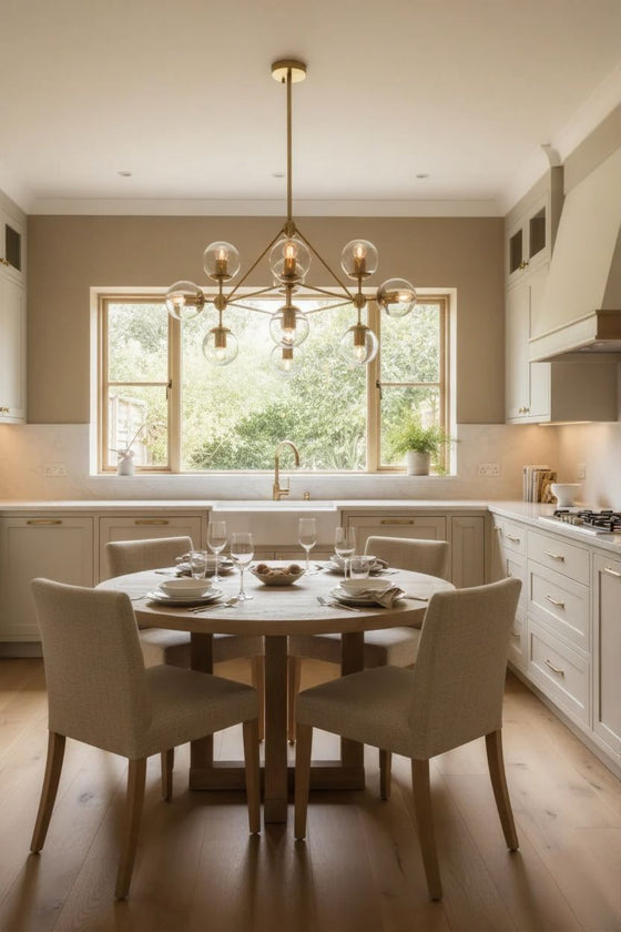 Modern kitchen with a round dining table and chairs, featuring a satin brass with glass globes chandelier and large windows.