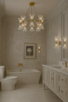 Luxurious bathroom with matching chandelier and sconces satin brass with clear glass, bathtub, and vanity.