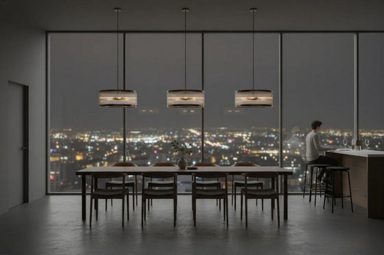 Modern dining room with a large window view of a city skyline at night. Satin brass pendant with clear glass.