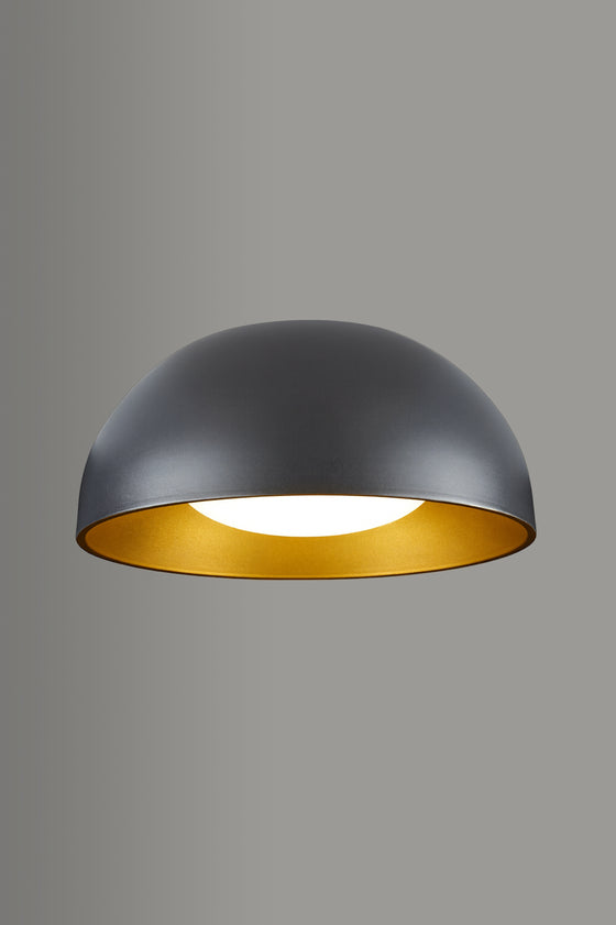 Modern pendant light with black exterior and gold interior on a gray background