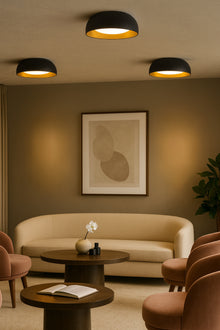  Modern living room with beige sofa, round wooden tables, and abstract art on the wall. Black and gold LED ceiling light.