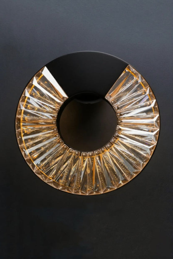 Decorative circular glass sconce in matte black with textured design on a dark background