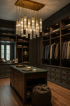 Luxurious walk-in closet with wooden furniture, hanging clothes, and a satin brass multi light chandelier.