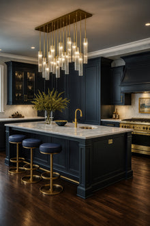 Modern kitchen with dark blue island, satin brass fixtures, and a satin brass chandelier with clear glass.