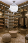 Luxurious walk-in closet with shelves of shoes, bags, and clothing, illuminated by a chrome pendant glass chandelier.