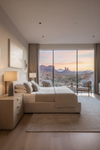 Modern bedroom with a large window view of desert landscape and mountains. Grey Ceramic base with linen fabric shade, satin brass finish.