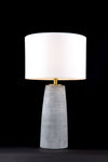A Harper geometric grey ceramic table lamp with satin brass and a white fabric shade on a black background