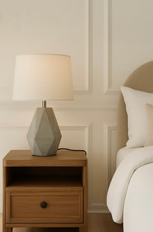  Contemporary concrete table lamp with fabric linen shade with sculptural stone base on wood nightstand in luxury bedroom