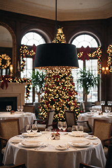  Decorated restaurant interior with Christmas tree and festive decorations. Black and gold shade chandelier