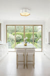 Modern kitchen with white island and stools, large window view of garden. Flushmount white flower design ceiling light.