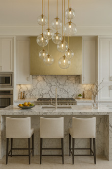  Modern kitchen with marble countertop, satin brass and glass globe pendant lights, and bar stools.