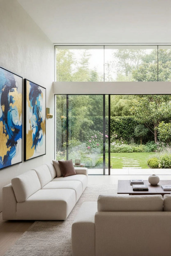 Modern living room with a large window view of a garden. LED satin brass wall sconces.