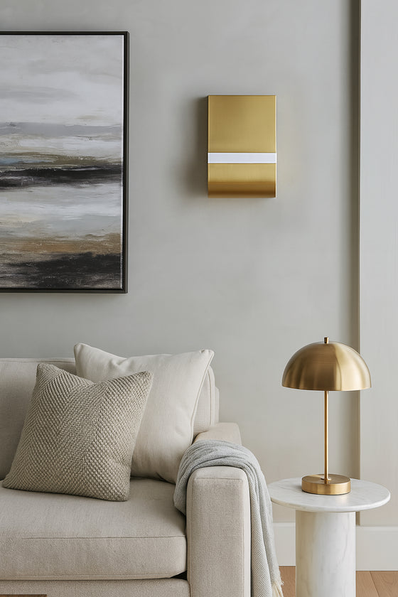 Modern living room with a beige sofa, gold lamp, and abstract painting. LED satin brass wall sconces. 