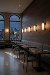Dining area with tables, chairs, and matte black with glass wall lights in a restaurant with cityscape view.