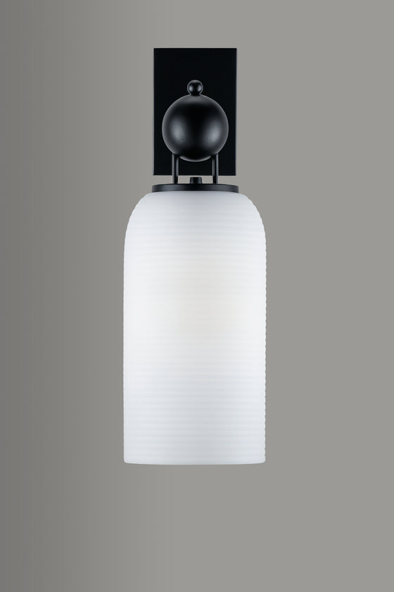 Wall-mounted light fixture with black fixture and white glass shade on a gray background