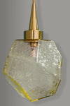 Decorative pendant light with textured amber glass shade and brass fixture on a gray background