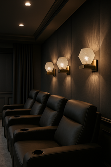  Dark movie theater with leather seats and satin brass and glass wall lights.