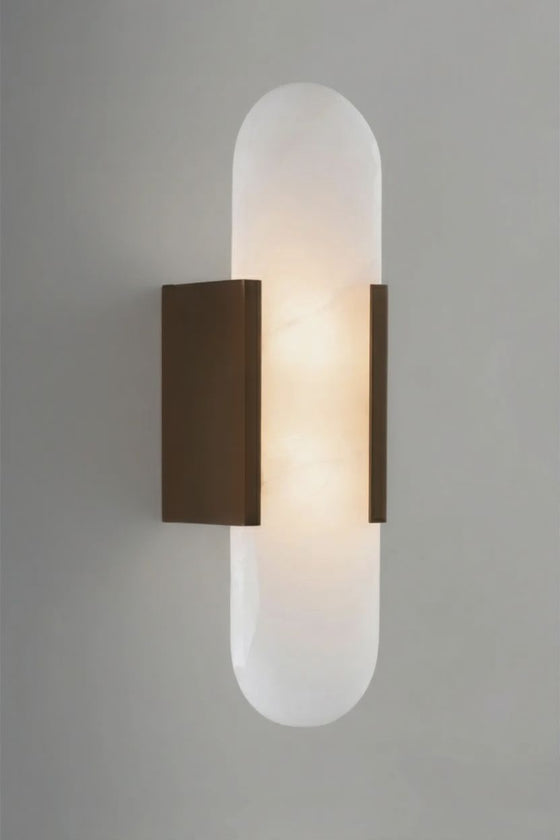 Wall-mounted bronze and alabaster light fixture with a cylindrical glass shade on a gray background