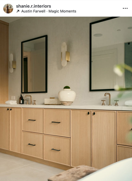 Modern bathroom with wooden cabinets, mirrors, and satin brass alabaster LED wall sconces.