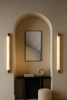  Modern interior design with wall alabaster satin brass LED sconces, a framed artwork, and a small table.