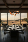 Dining room with large windows overlooking a scenic landscape. Matte black with ceramic shades pendant chandelier, LED.
