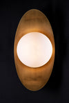 A LED wall sconce featuring a satin brass leaf-shaped backplate with a spherical milk glass orb.