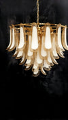 Chandelier with gold frame and amber and white glass shades on a black background