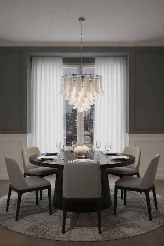 Dining room with round table and chairs under a modern silver frame with clear and white glass chandelier.
