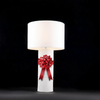 White table lamp with a red bow on a black background