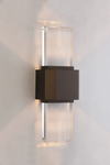 Modern wall-mounted bronze and glass light fixture on a plain wall.
