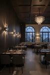Wall Sconce polished Nickel Dark restaurant interior with tables, chairs, and a chandelier.