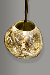 Satin Brass pendant light with a textured glass shade on a gray background