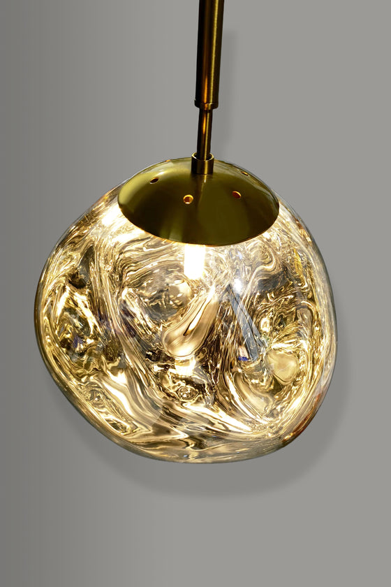 Satin Brass pendant light with a textured glass shade on a gray background
