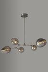 Modern stainless steel chandelier with multiple glass shades on a gray background