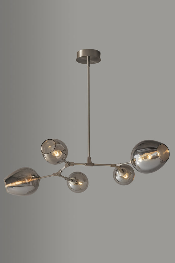 Modern stainless steel chandelier with multiple glass shades on a gray background