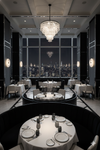 Elegant restaurant interior with tables set for dinner, large window view of city skyline, and chandelier and matte black alabaster wall sconces.