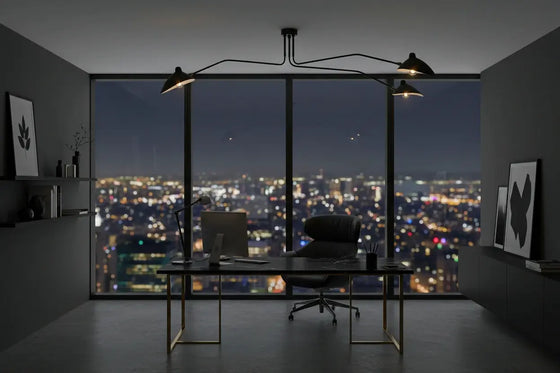 Modern pendant in black with office desk with chair and computer monitor in a room with large windows showing a cityscape at night.