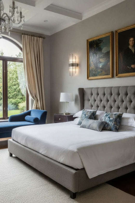 Luxurious bedroom with glass sconces and a large bed, armchair, and framed artworks on the wall.