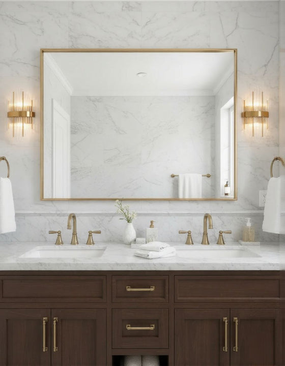 Bathroom vanity with marble countertop, satin brass light fixtures, and large mirror.