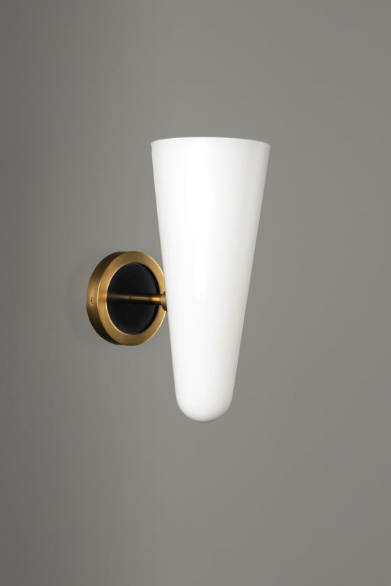Wall-mounted light fixture with white cone-shaped shade and gold base on a gray background