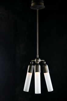  A modern bronze pendant light with three adjustable white glass bulbs, suspended from a ceiling by a metal chain.
