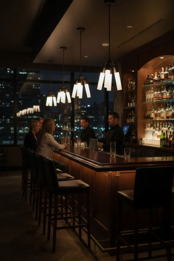 People sitting at a bar with cityscape view at night with 3 pendant lights